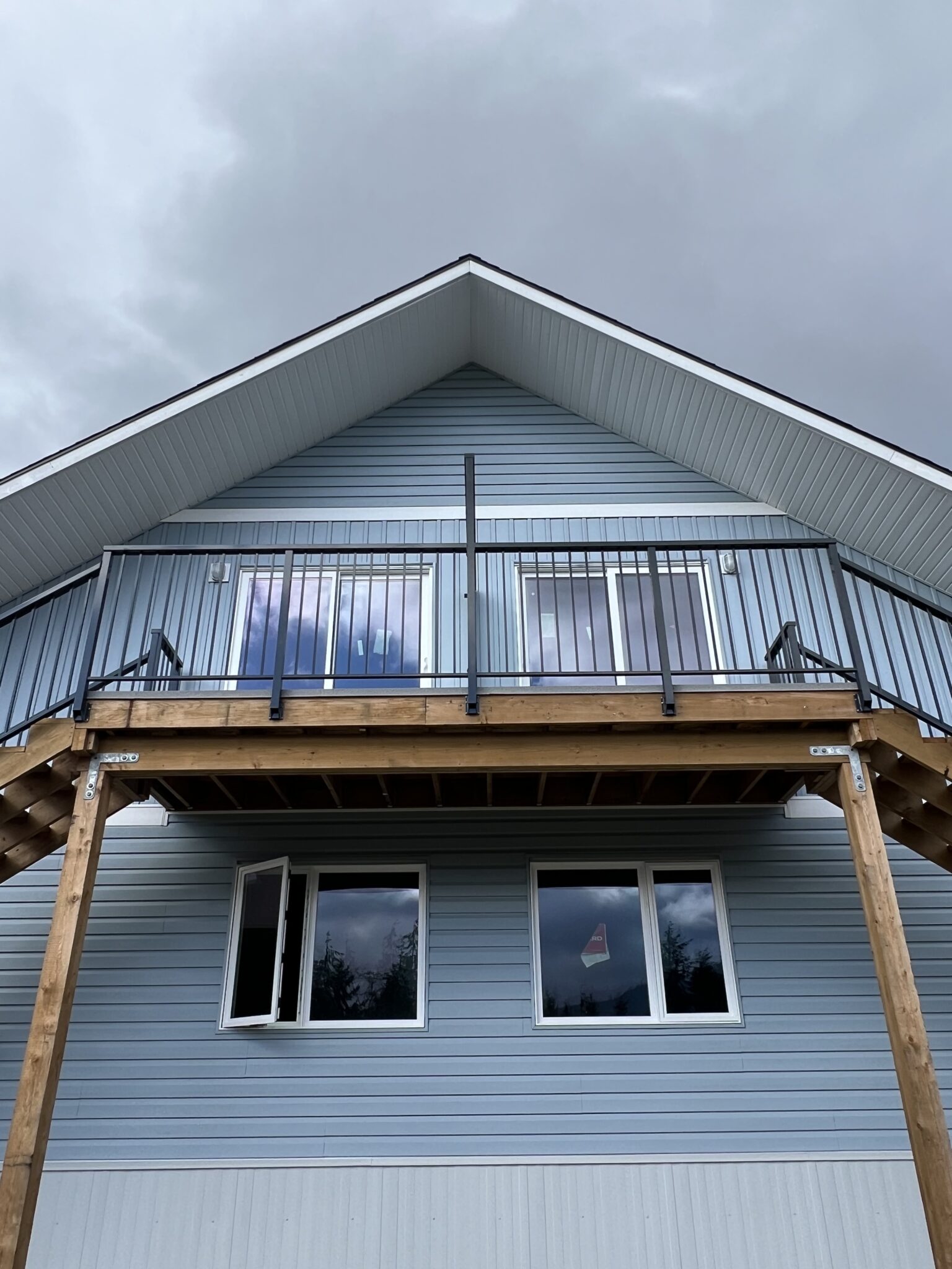 Front view of a raised deck railing on a Bamfield residence, featuring black aluminum balusters mounted above wood support posts.