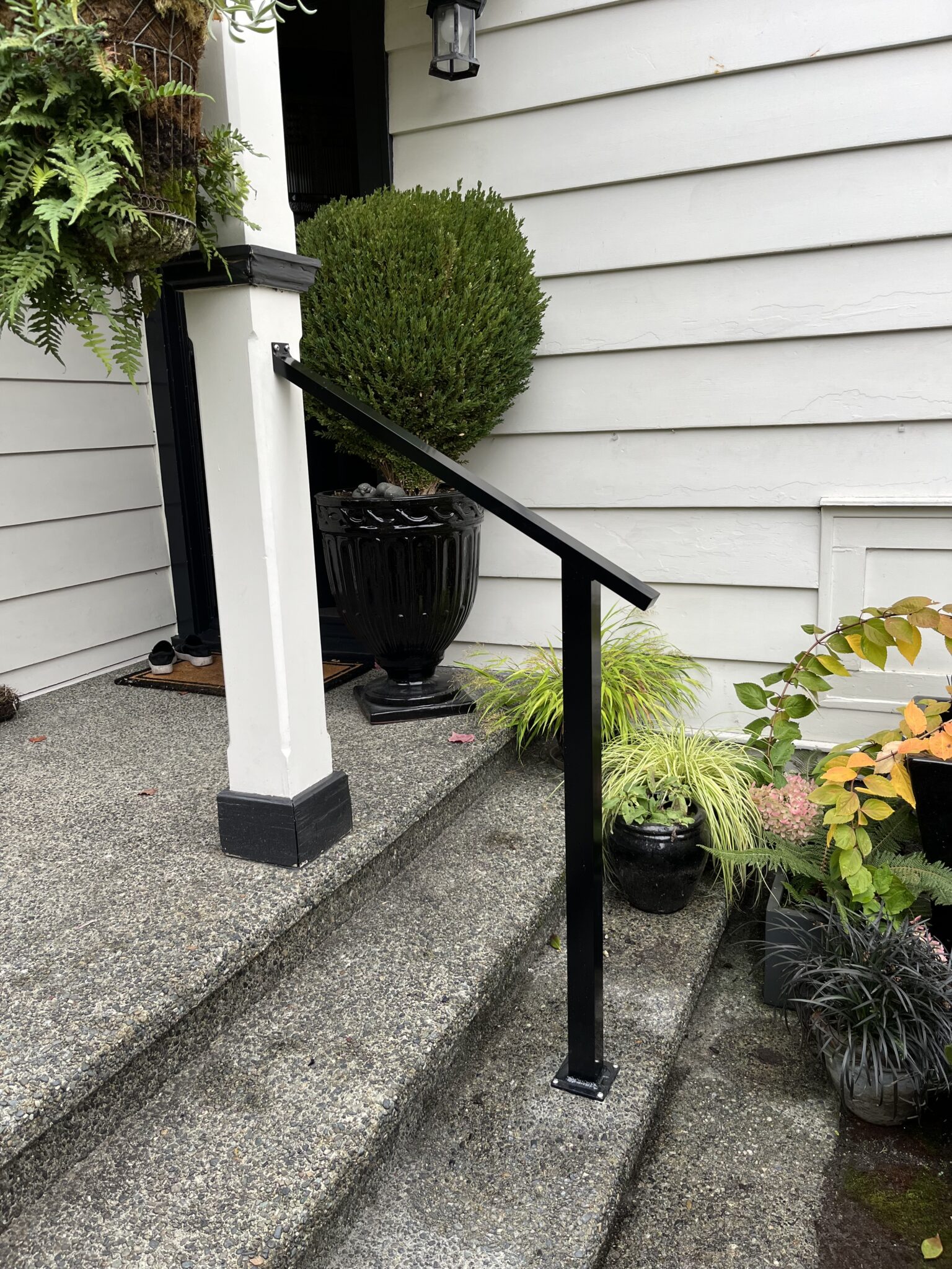 Black metal handrail added to the front steps of a Ladysmith home, providing a sturdy and simple railing for safe entry.