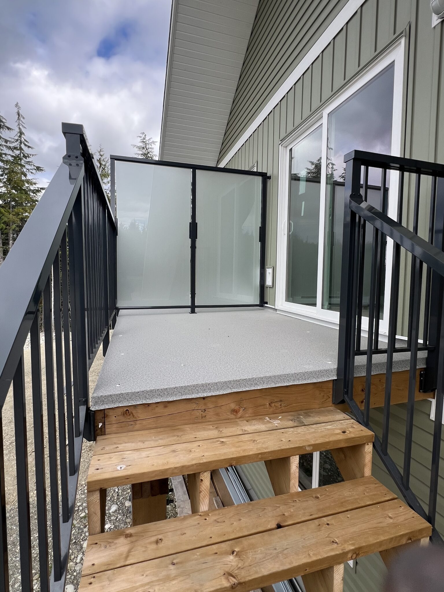 Deck landing on a Bamfield home with frosted privacy glass and custom aluminum railings.