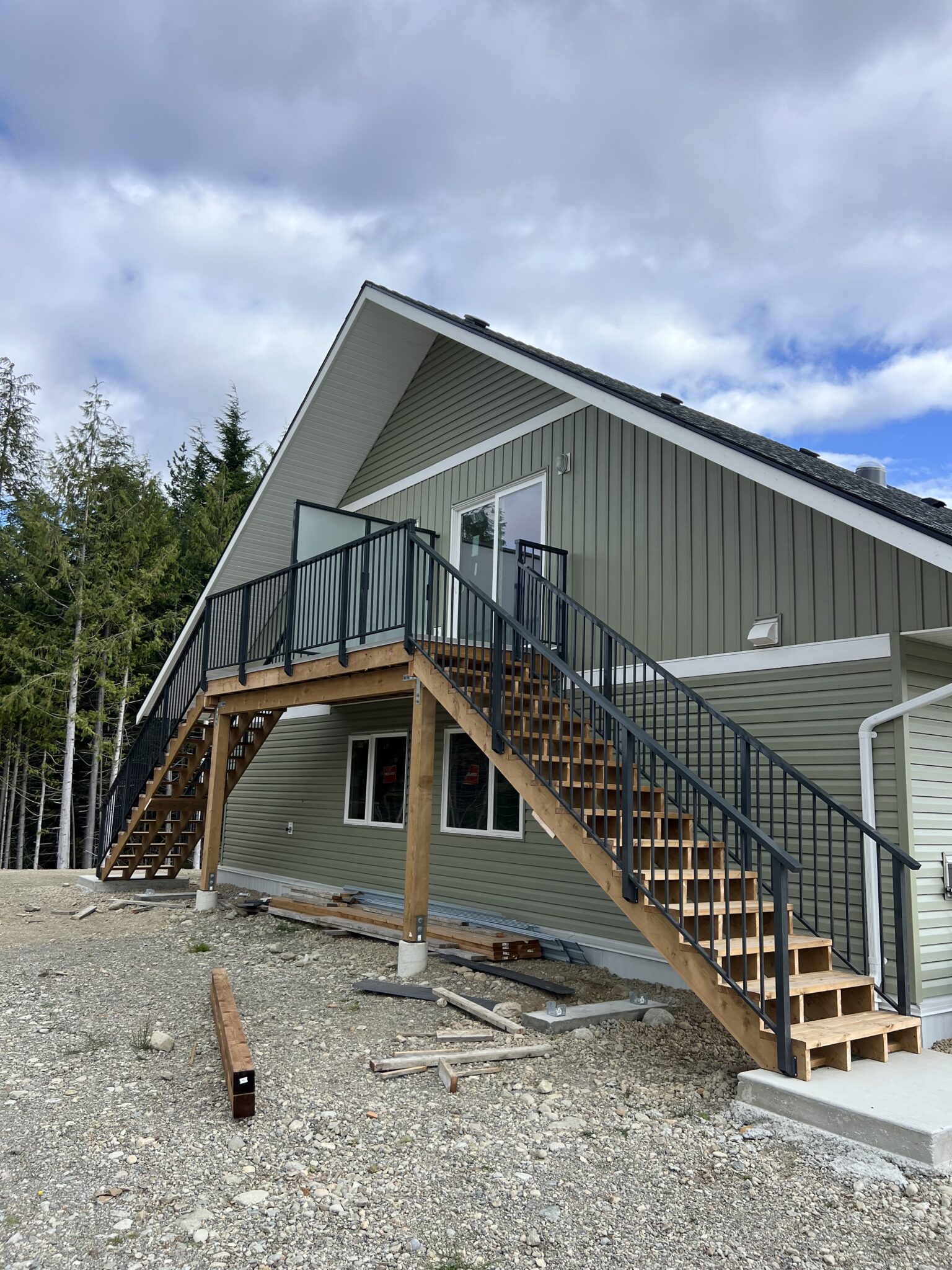 Black aluminum railing system along a wraparound exterior staircase on a Bamfield property, blending modern railing lines with wood framing.